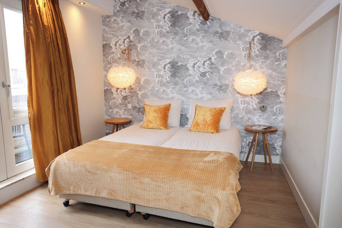Ein Schlafzimmer mit einem Bett, zwei Nachttischen, einem Fenster mit Vorhängen und einer strukturierten Wand.