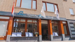 Un hotel con un letrero que dice "De Koningin Grand Caffee" y "Steeds Aan Zee Caffee".