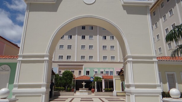 A hotel entrance with a large archway, a central fountain, and a building with multiple windows in the background. - Hotel Premier (São Luís)