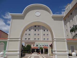 A hotel entrance with a large archway, a central fountain, and a building with multiple windows in the background. - Hotel Premier (São Luís)