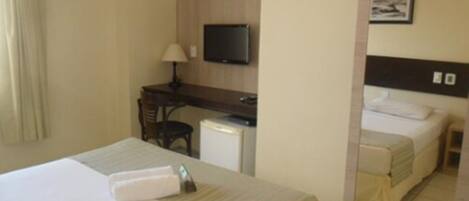 Une chambre d’hôtel comprenant un lit, un bureau avec une chaise, une télévision et un miroir.