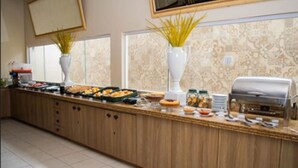A buffet setup with various food items, a grill, and decorative plants. - Hotel Premier (São Luís)