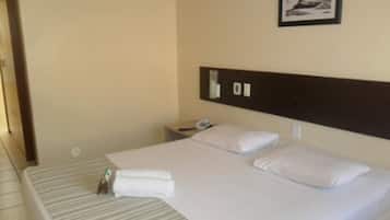 A hotel room with a bed, a nightstand, a phone, and a framed picture on the wall.