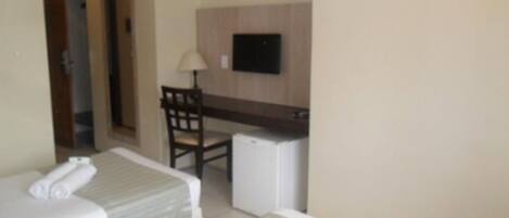 Habitación de hotel con dos camas, un escritorio, una silla y un refrigerador pequeño.