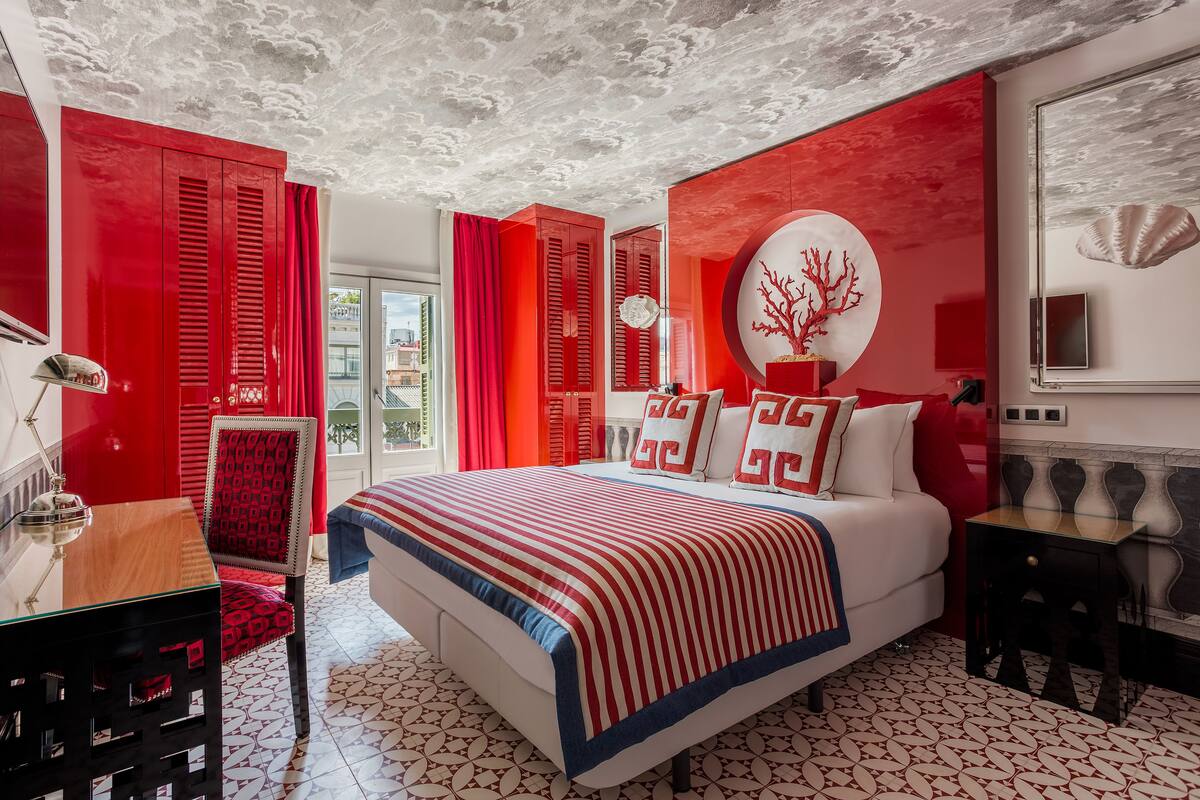 A modern bedroom with a large bed, red and white decor, and a unique ceiling design.