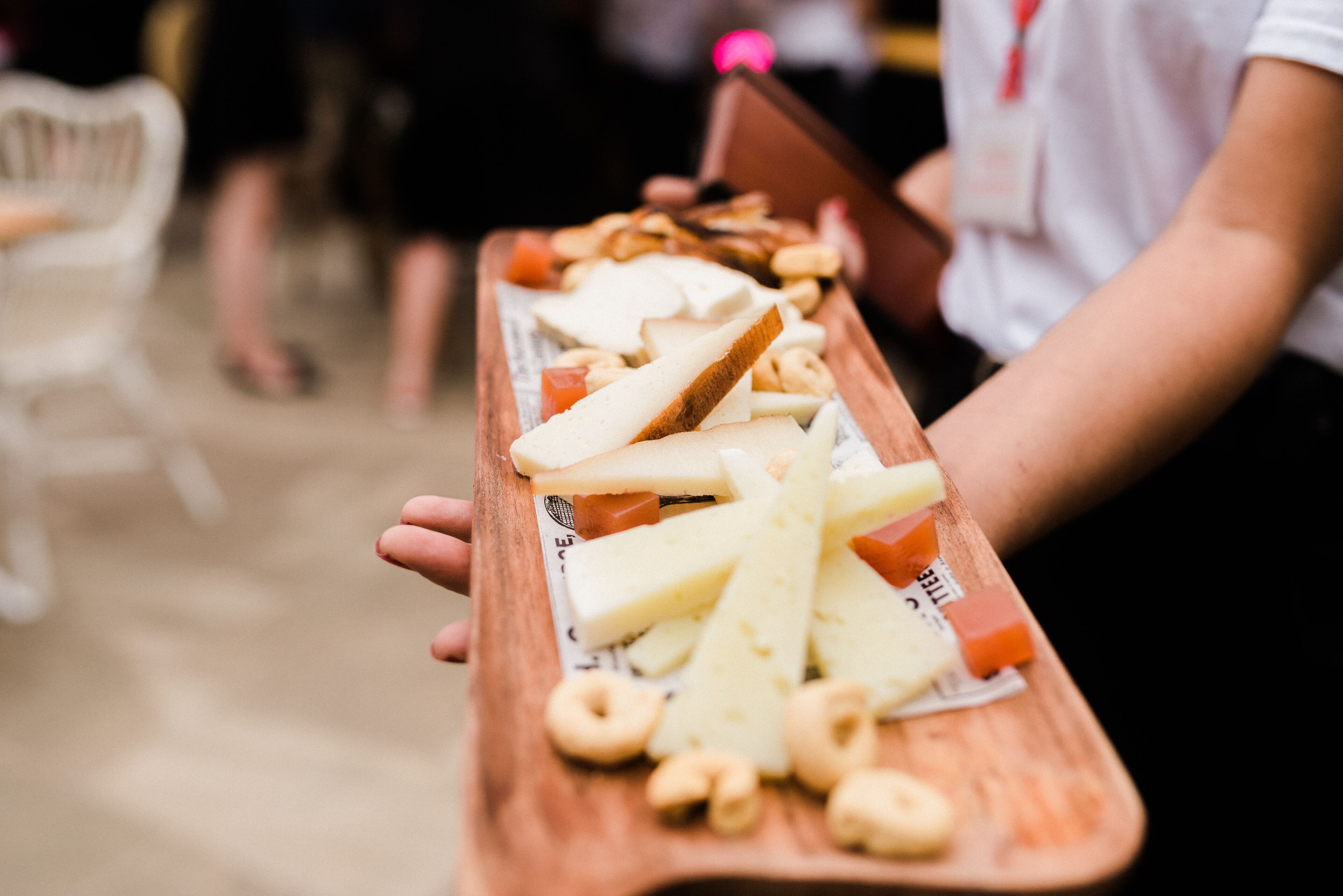 Un plateau en bois contenant divers fromages et amuse-gueules.