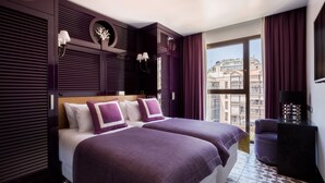 A hotel room with two beds, a large window with a view of buildings, and a balcony with a chair. - Room Mate Anna, Barcelona (Barcelona)