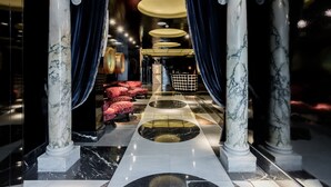 A marble-floored lobby with columns, red seating, and a checkered floor pattern. - Room Mate Anna, Barcelona (Barcelona)