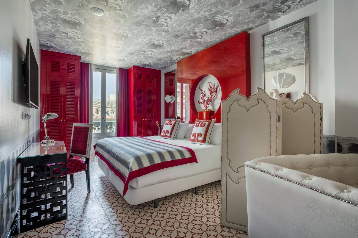 A bedroom with a bed, a chair, a TV, and a table.