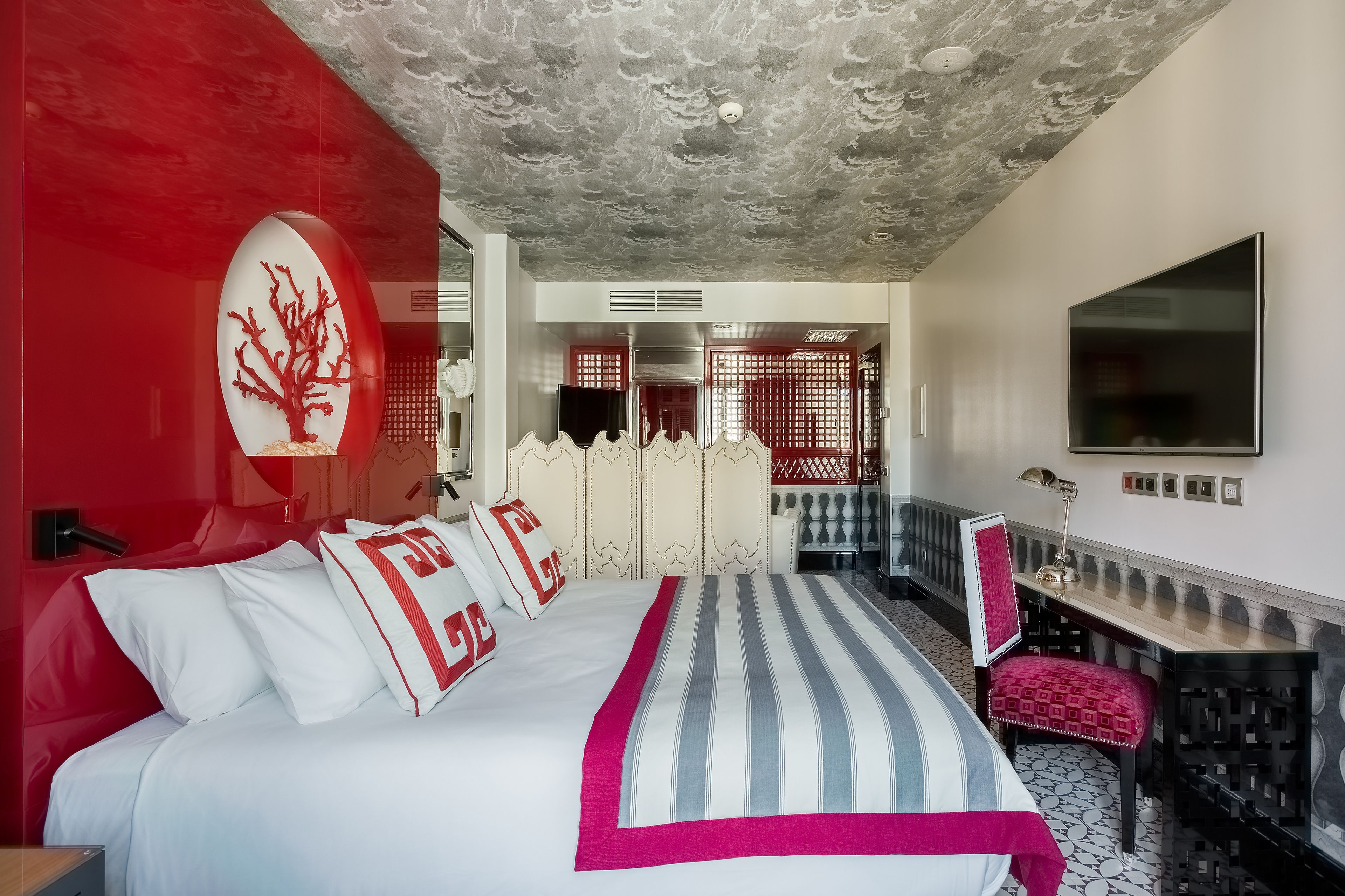 Una habitación de hotel moderna con una cama grande, un televisor y un escritorio con una silla.
