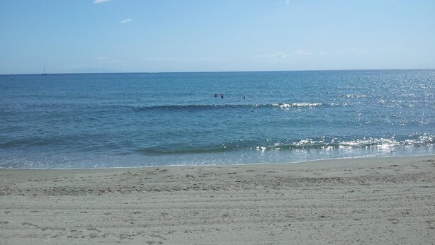 Ein Strand mit blauem Himmel und ruhigem Wasser.