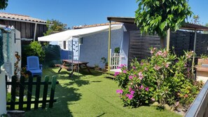 Een achtertuin met een picknicktafel, een witte tent en een houten omheining.
