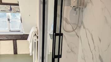 Un baño moderno con cabina de ducha de vidrio, inodoro empotrado y ventana con vistas.
