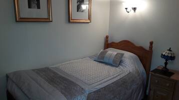 Ein Schlafzimmer mit einem Bett, zwei gerahmten Bildern an der Wand, einer Nachttischlampe und einem Nachttisch.