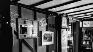 A black and white interior with a leather sofa, patterned cushions, and a vintage clock. - The Four Horseshoes (Eye)