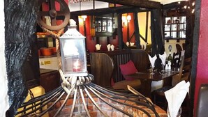 A restaurant interior with a brick fireplace, wooden seating, and a table set for dining. - The Four Horseshoes (Eye)