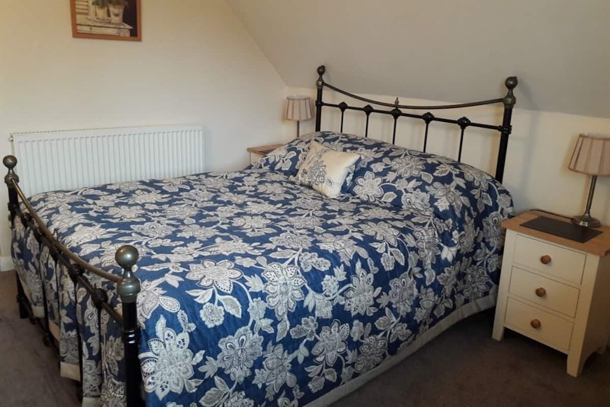 Un dormitorio con cama, mesitas de noche y un radiador.
