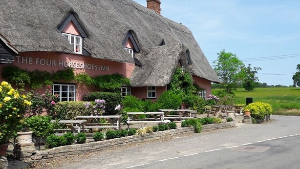 A traditional thatched-roof building with a sign reading "The Four Horseshoes Inn." - The Four Horseshoes (Eye)