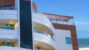 A modern hotel with multiple balconies, a prominent staircase, and a view of the ocean. - Calhau Praia Hotel (São Luís)