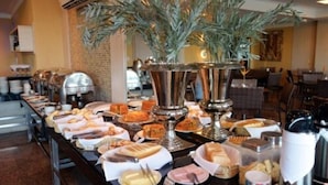A buffet setup with various food items and a decorative plant. - Calhau Praia Hotel (São Luís)