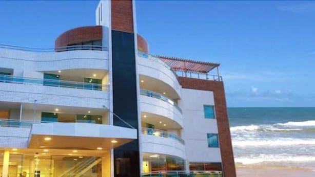 A multi-story hotel with balconies, a pool area, and a view of the ocean. - Calhau Praia Hotel (São Luís)