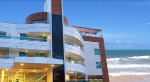 A multi-story hotel with balconies, a pool area, and a view of the ocean. - Calhau Praia Hotel (São Luís)