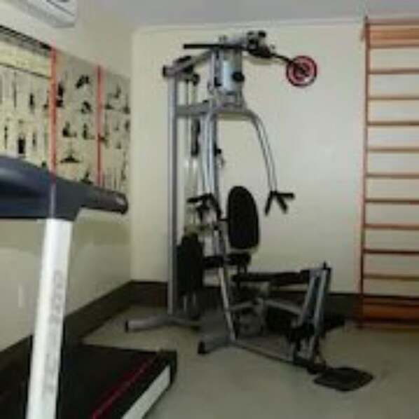A gym with a treadmill, weight machines, and a pull-up bar. - Calhau Praia Hotel (São Luís)