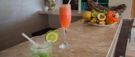 A bar area with a drink in a tall glass and a plate of fruits.