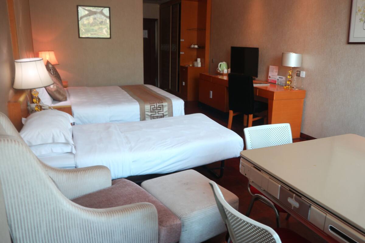 Habitación de hotel con dos camas, un escritorio, una silla y una mesa.