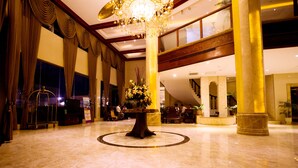 Un lobby espacioso con una mesa redonda central, grandes columnas y una araña.