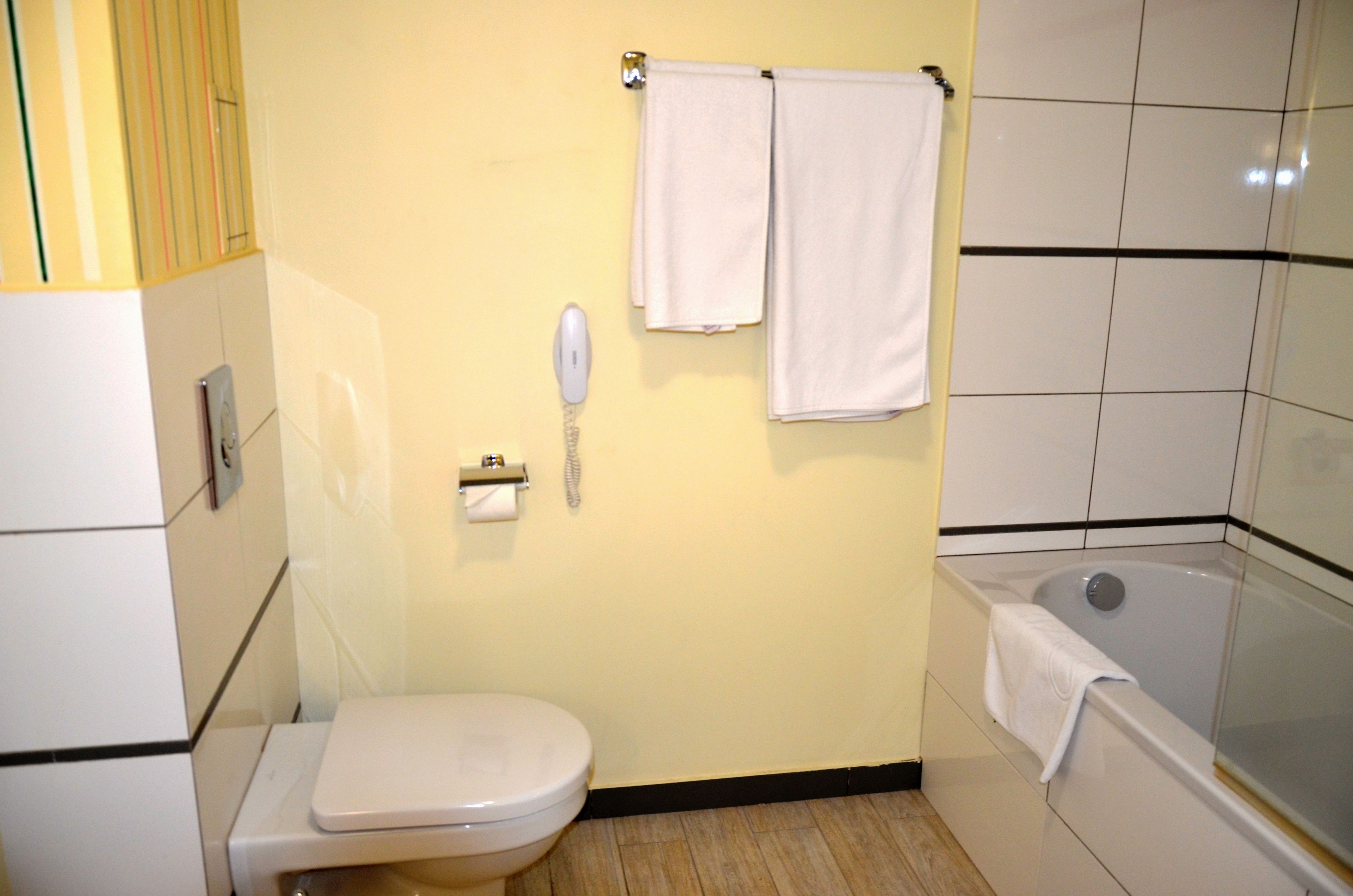 Een kleine badkamer met toilet, wastafel, telefoon en bad.