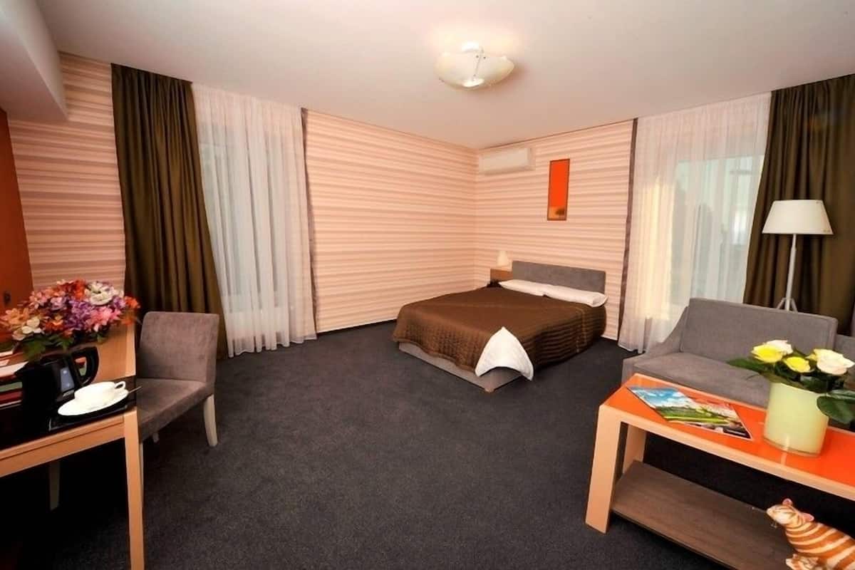 Ein Hotelzimmer mit Bett, Sofa, Schreibtisch und Lampe.