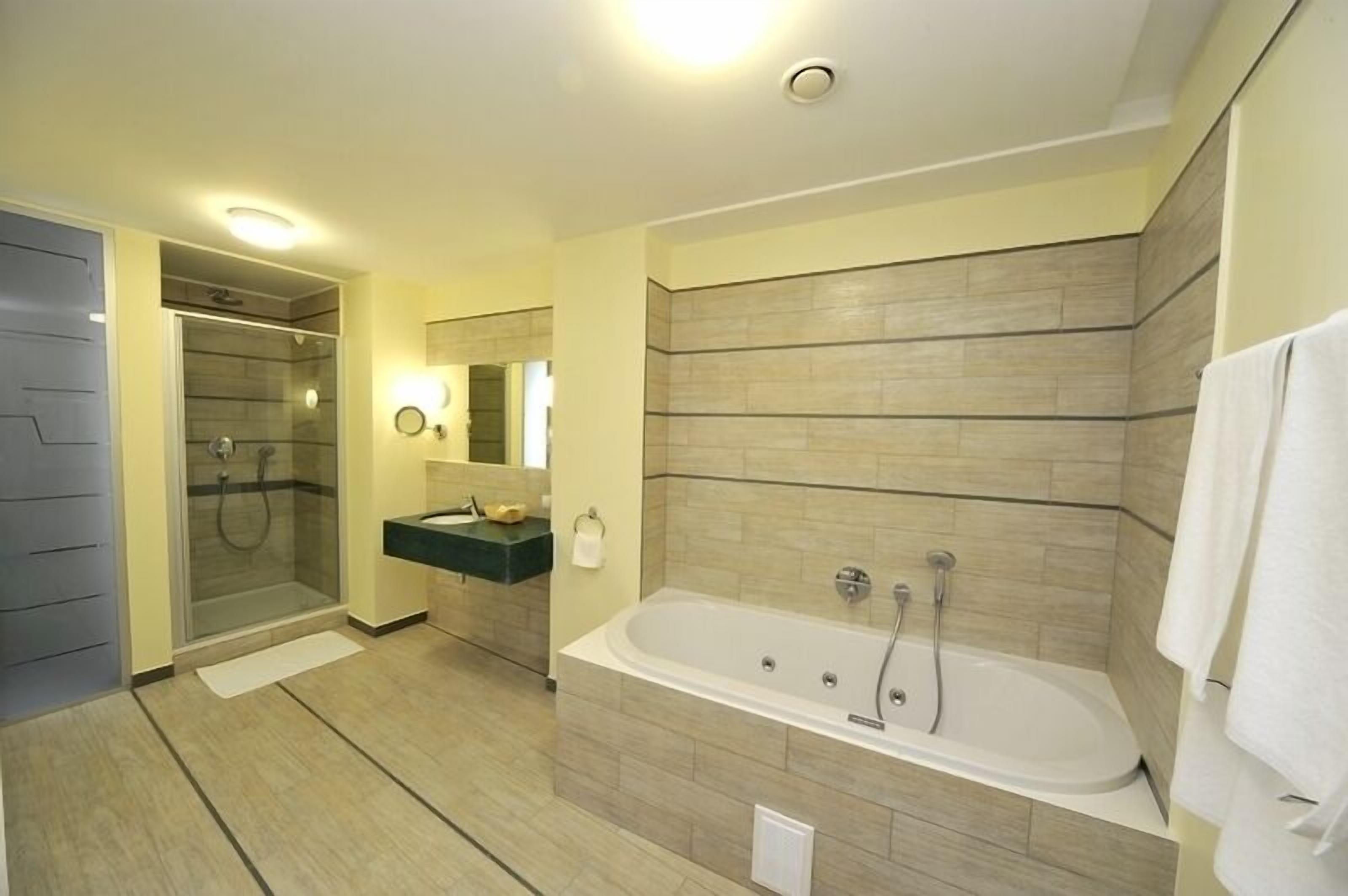 A modern bathroom with a walk-in shower, a freestanding bathtub, and a vanity with a mirror.