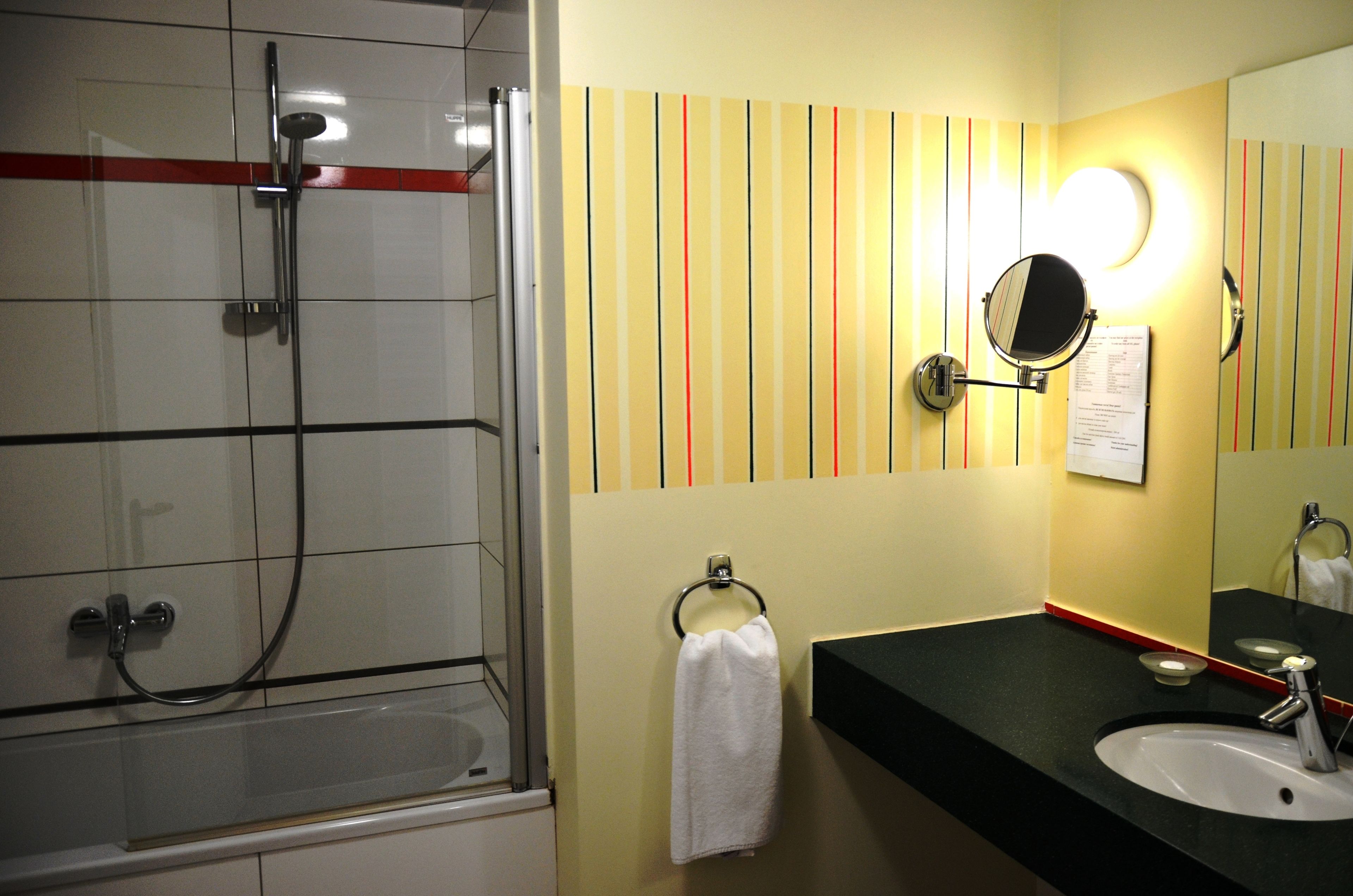 Un baño con ducha, lavamanos y espejo.