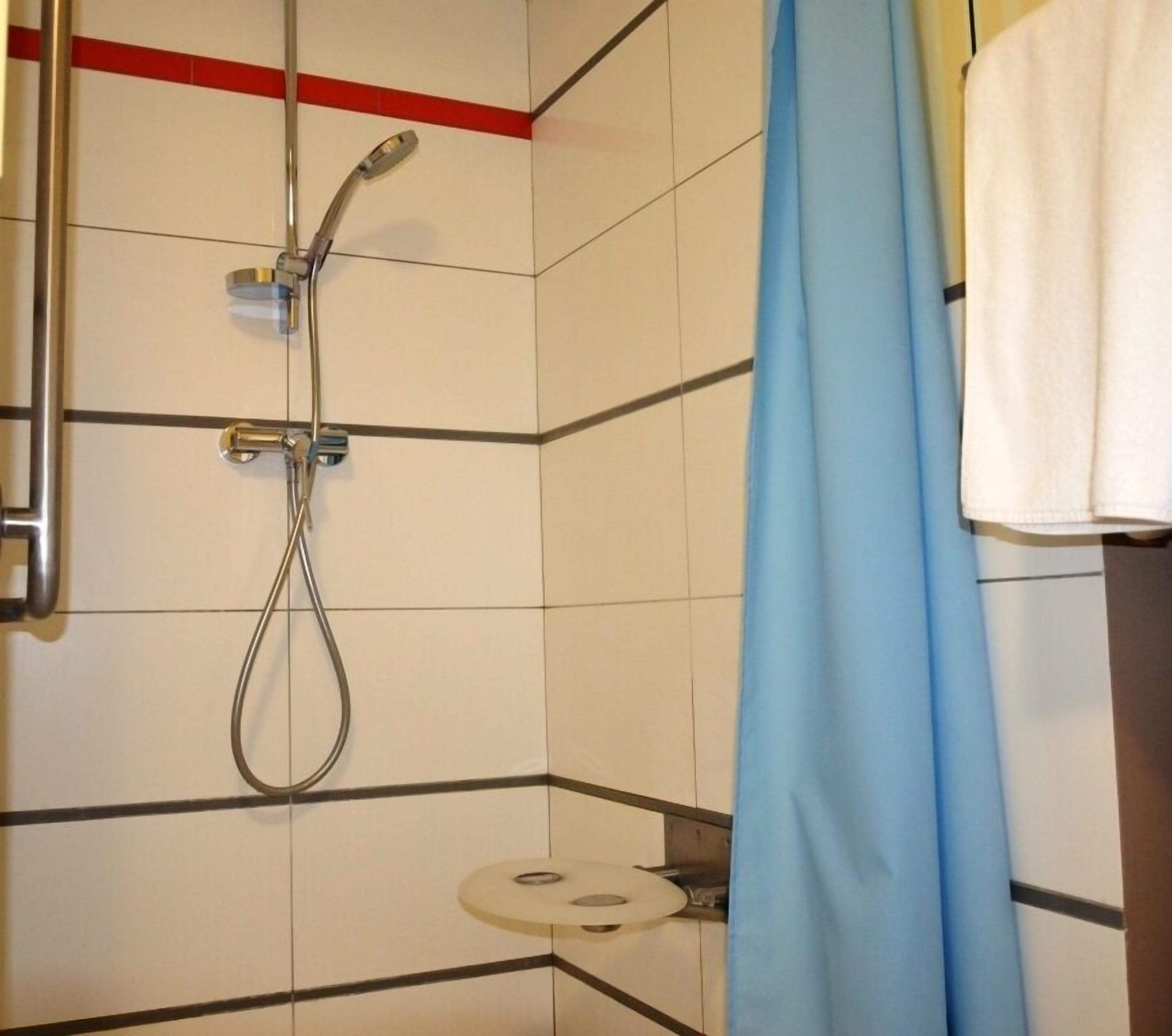A shower with a handheld showerhead and a wall-mounted faucet.