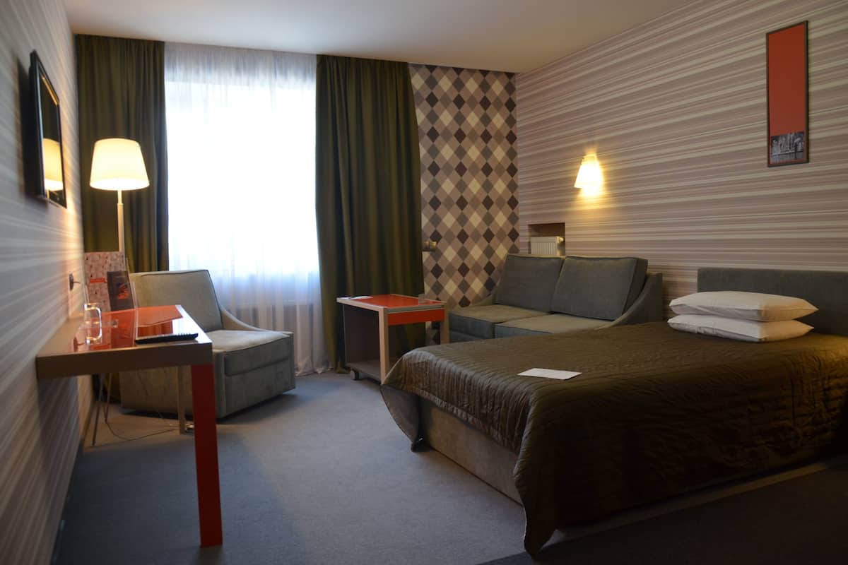 Ein Hotelzimmer mit Bett, Schreibtisch, Stuhl, kleinem Tisch und Lampe.