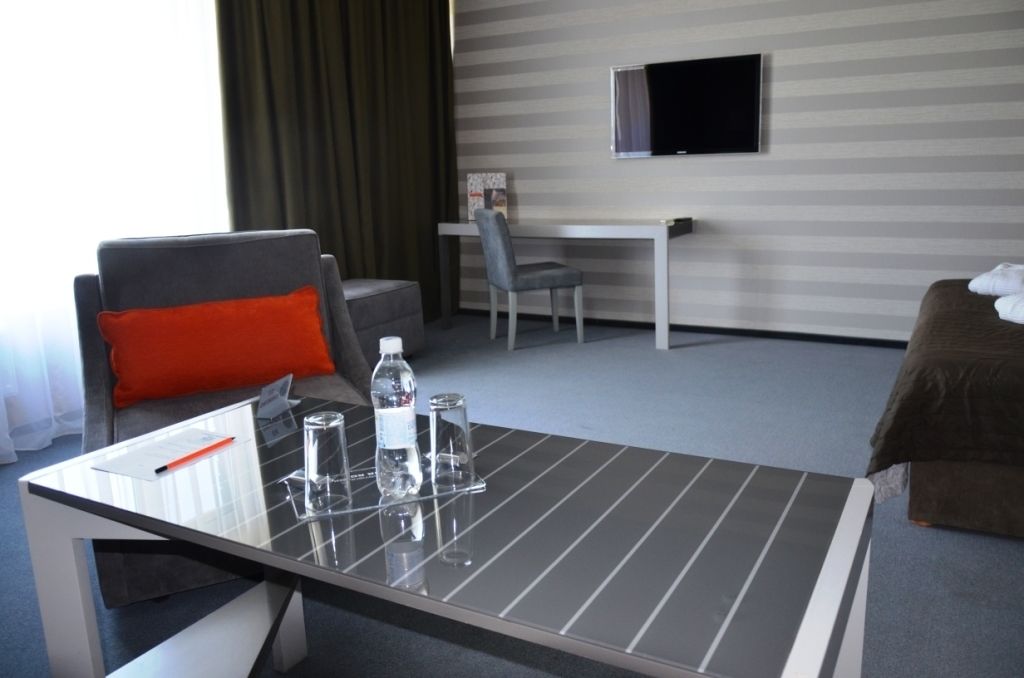 A hotel room with a bed, a desk, a chair, and a TV on the wall.