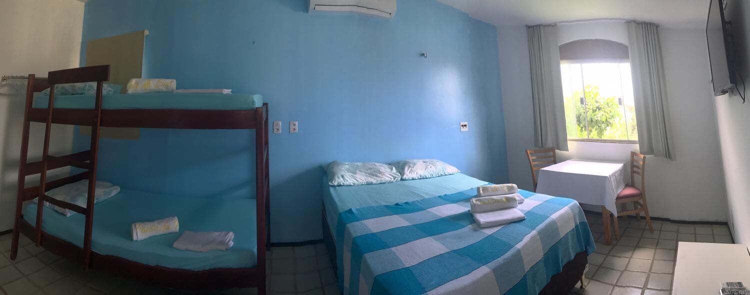 A room with a bunk bed, a single bed, a desk, and a chair.