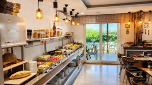 A buffet with various food items, a seating area with tables and chairs, and a view of greenery outside.