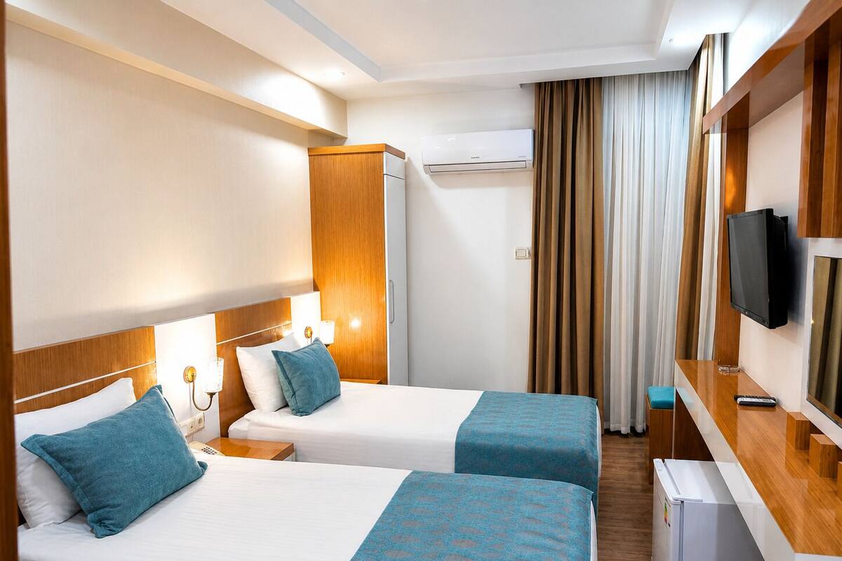 Een hotelkamer met twee bedden, een televisie, een minibar en een airconditioner.