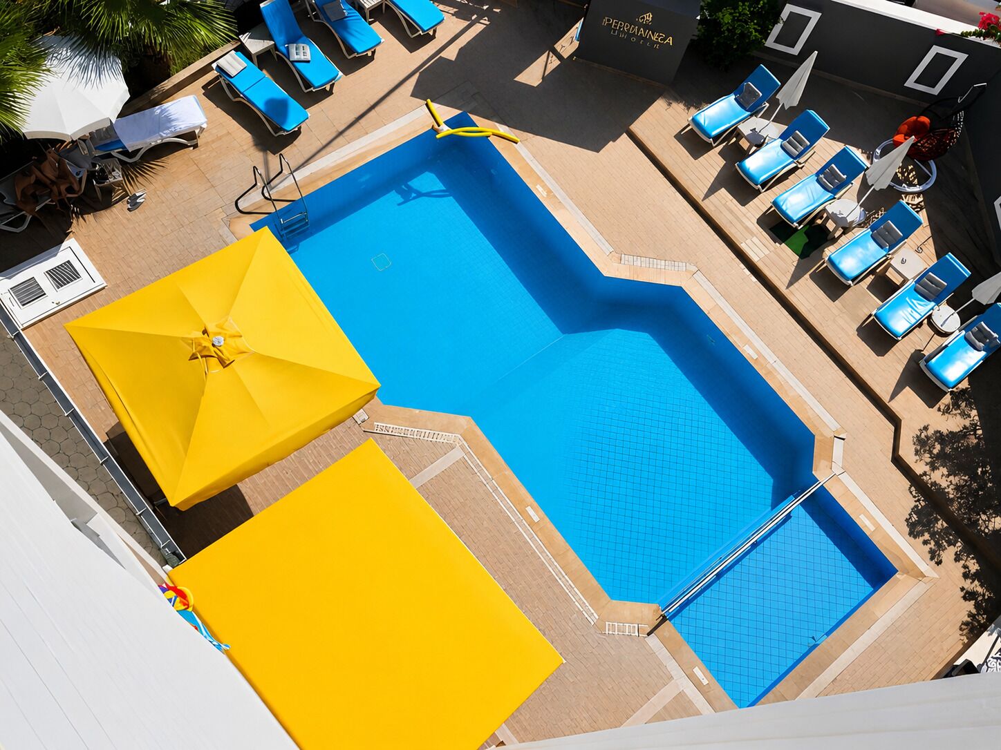 Una piscina en la azotea con agua azul, rodeada de sillas de descanso azules y sombrillas amarillas.