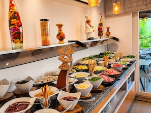 A buffet with various food items and decorative glassware on shelves. - Esperanza Hotel (Antalya)