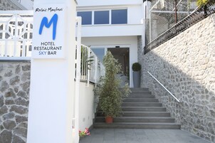 Entrada de un hotel con un letrero que dice 'Relais Manfredi' y una escalera que lleva a la entrada.