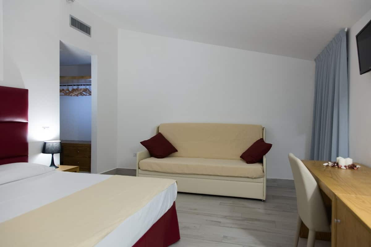 A hotel room with a bed, a sofa, a desk, and a chair.