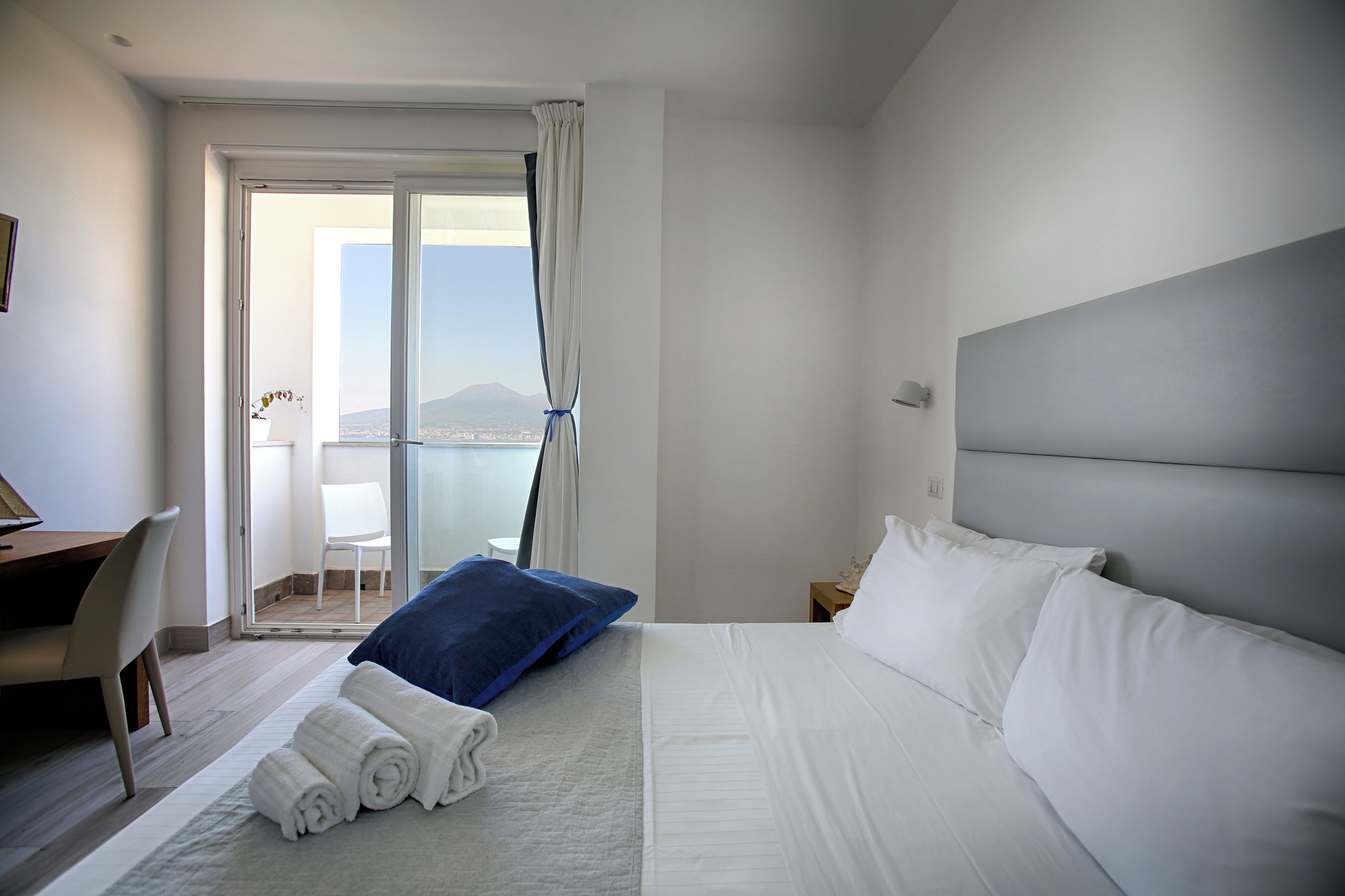 A hotel room with a bed, a desk, and a chair.