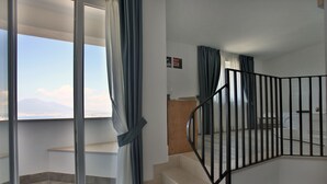 A modern apartment with a balcony, a staircase with a black railing, and a view of mountains. - Relais Manfredi (Castellammare di Stabia)