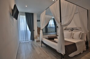A bedroom with a four-poster bed, a television mounted on the wall, and a staircase leading to an upper level. - Relais Manfredi (Castellammare di Stabia)