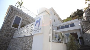 A hotel entrance with a stone facade, a sign for a restaurant and sky bar, and a staircase leading to a modern building. - Relais Manfredi (Castellammare di Stabia)