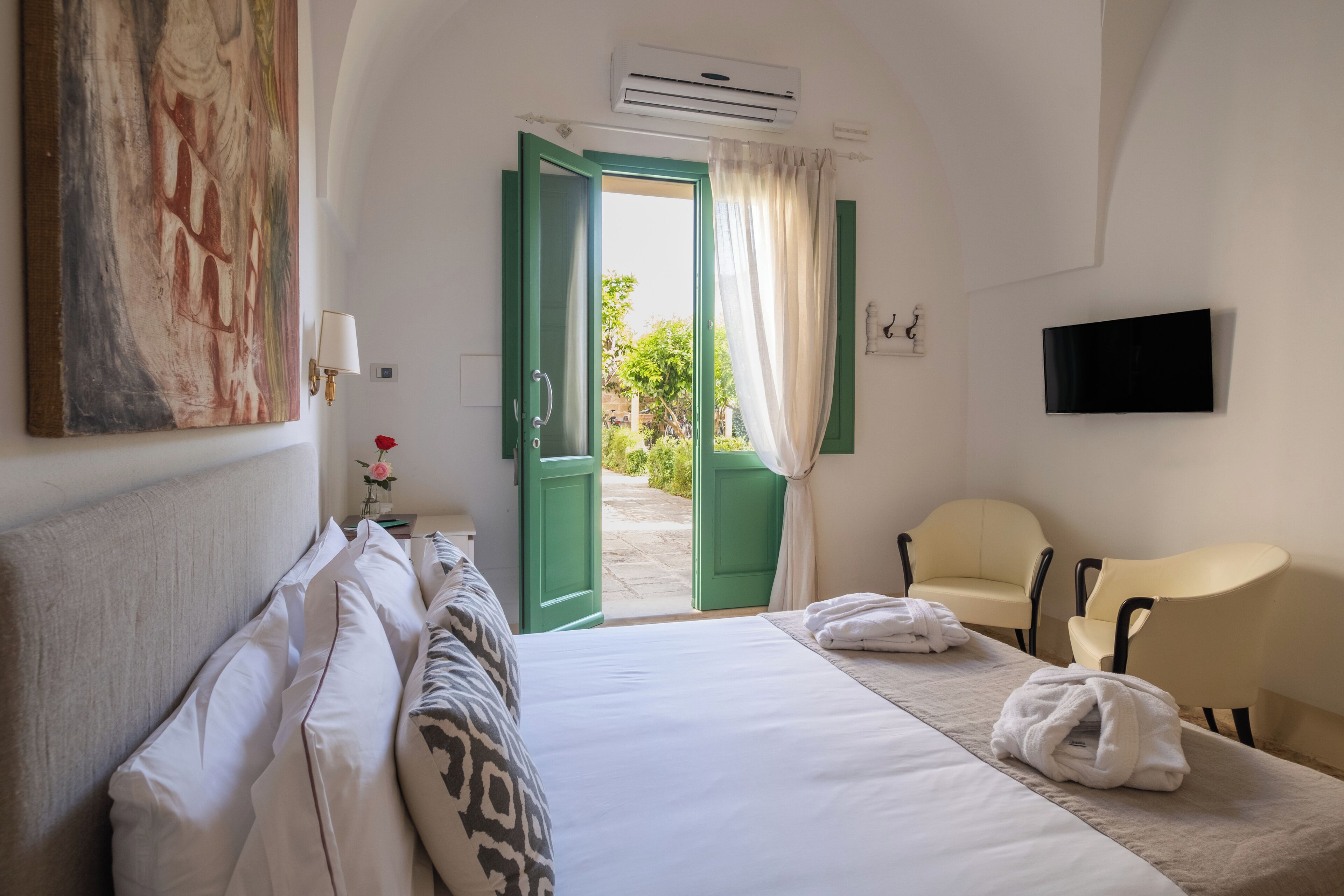 Une chambre d’hôtel avec un lit, une chaise, une télévision et un tableau au mur.