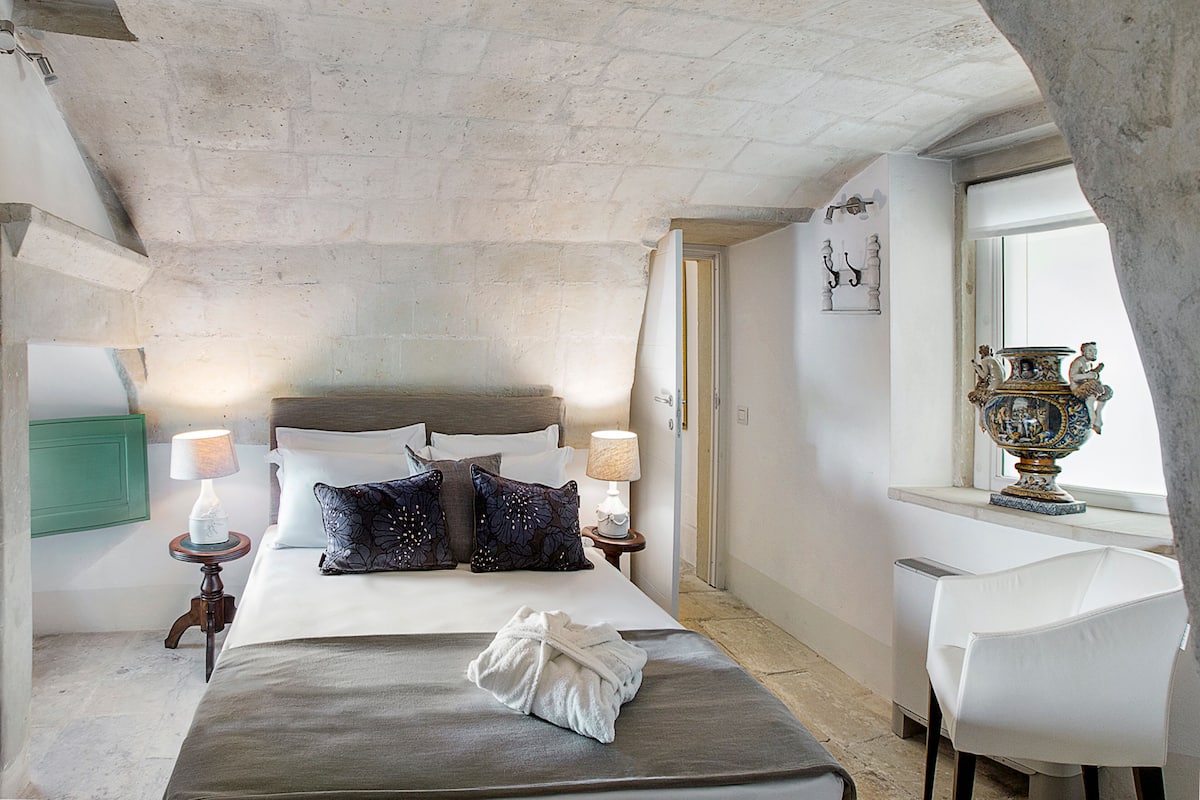 Une chambre d’hôtel avec un lit, des lampes de chevet, une chaise et un vase décoratif.